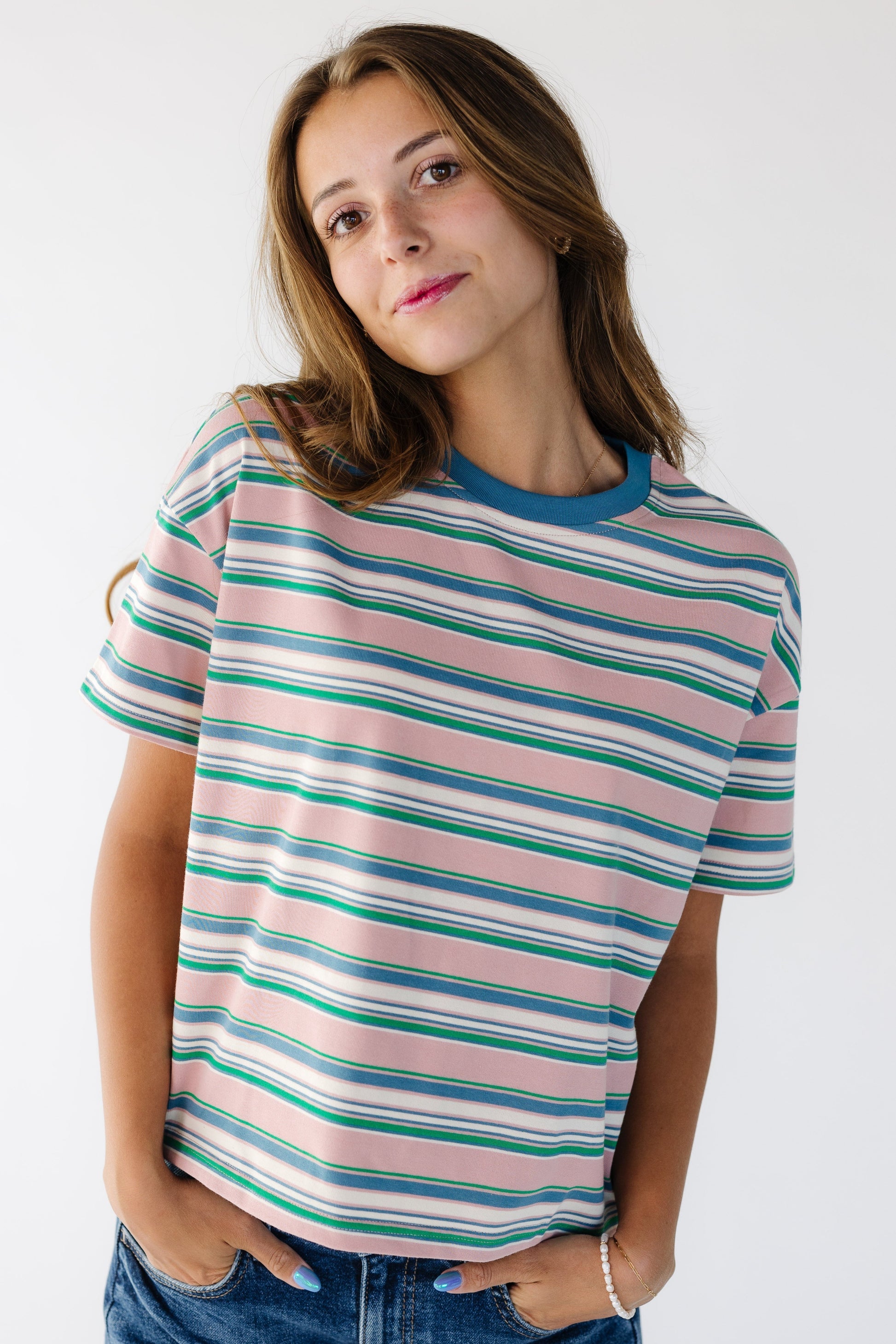 Woman wearing a boxy, loose fitting stripe tee in multicolor stripe.