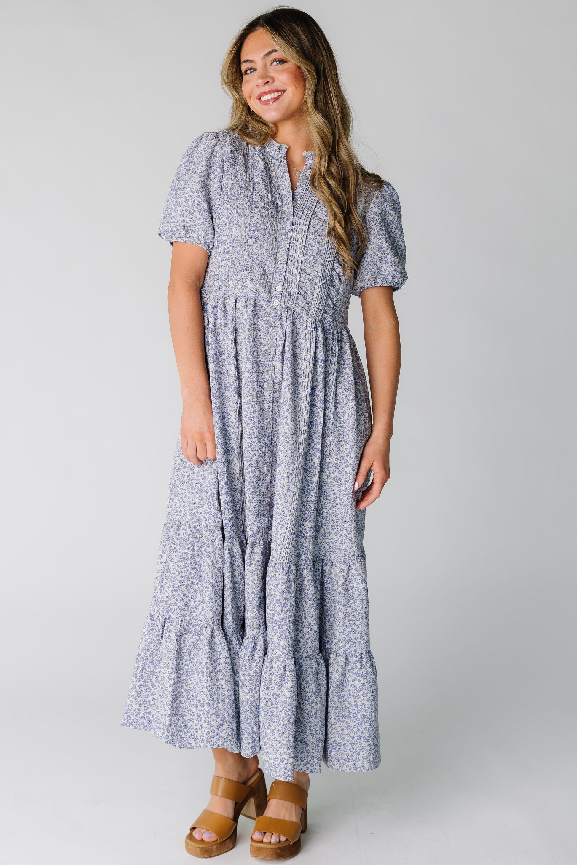 Woman wearing a purple floral button down midi dress with short sleeves.