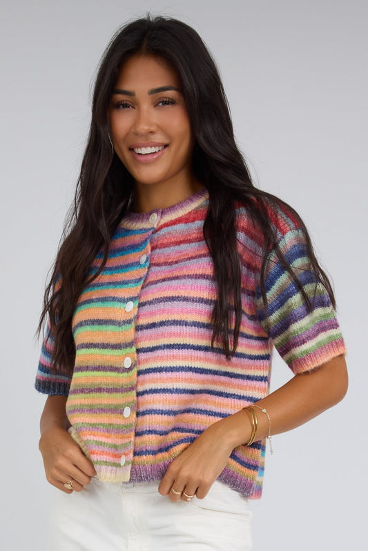 Young woman wearing a modest rainbow stripe button down cardigan with short sleeves.