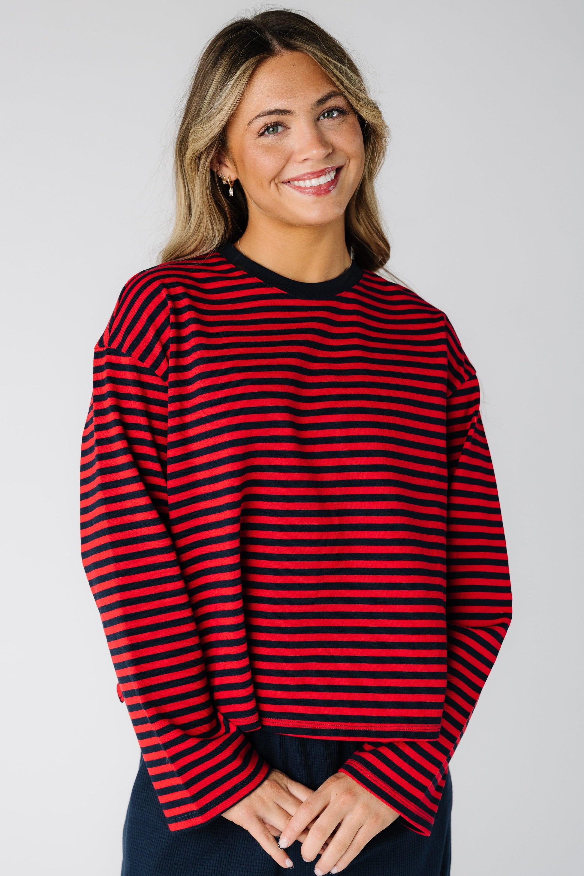 Woman wearing a  modest loose fitting stripe tee in red and navy with a crew neckline and long sleeves