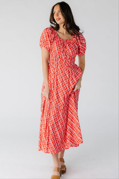 Woman wearing a red plaid midi dress with a close fitting bodice and waistband with a full flowy skirt.