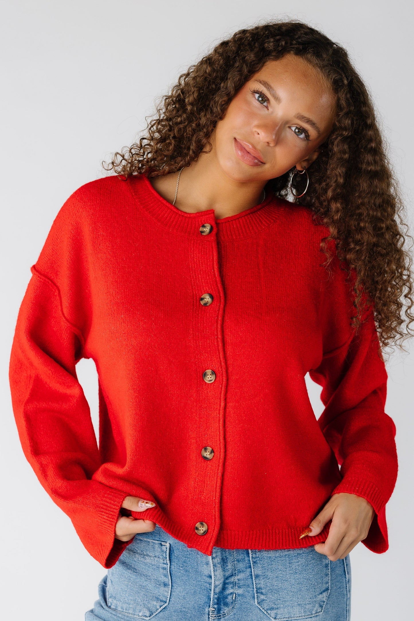 Woman wearing a red drop sleeve cardigan with long sleeves and exposed sleeves