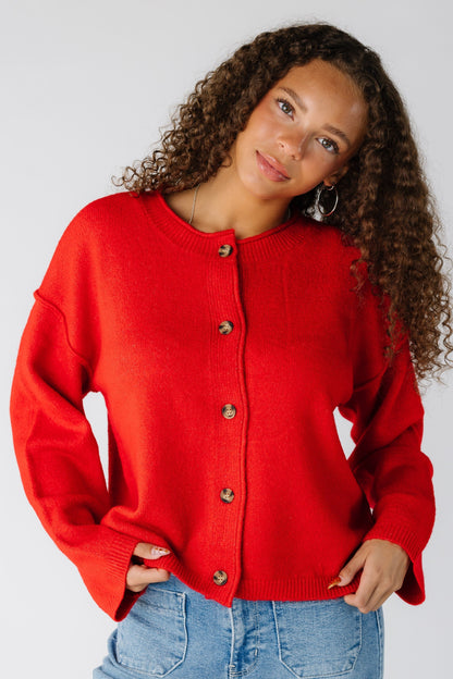 Woman wearing a red drop sleeve cardigan with long sleeves and exposed sleeves