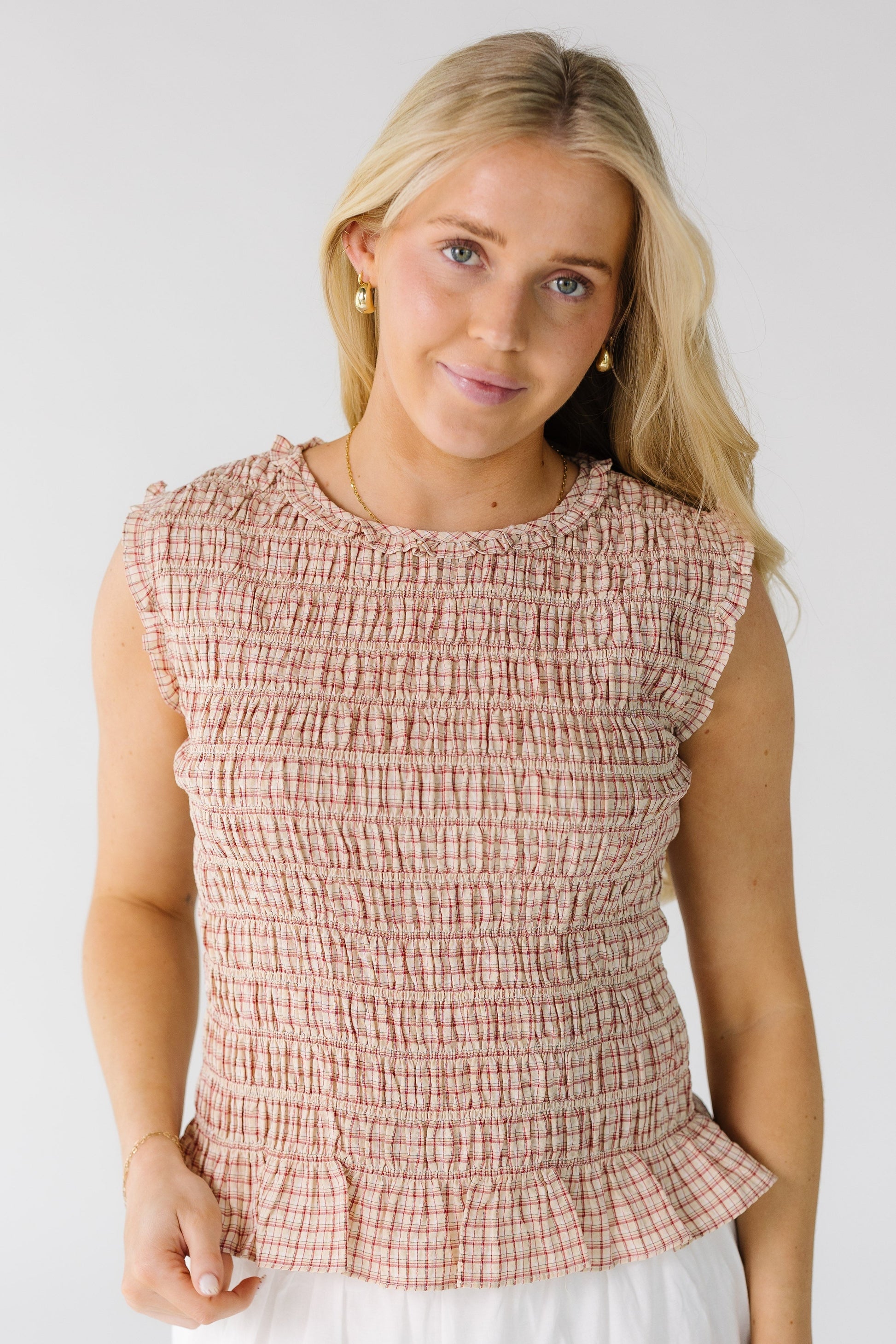 Woman wearing a smocked red plaid top.