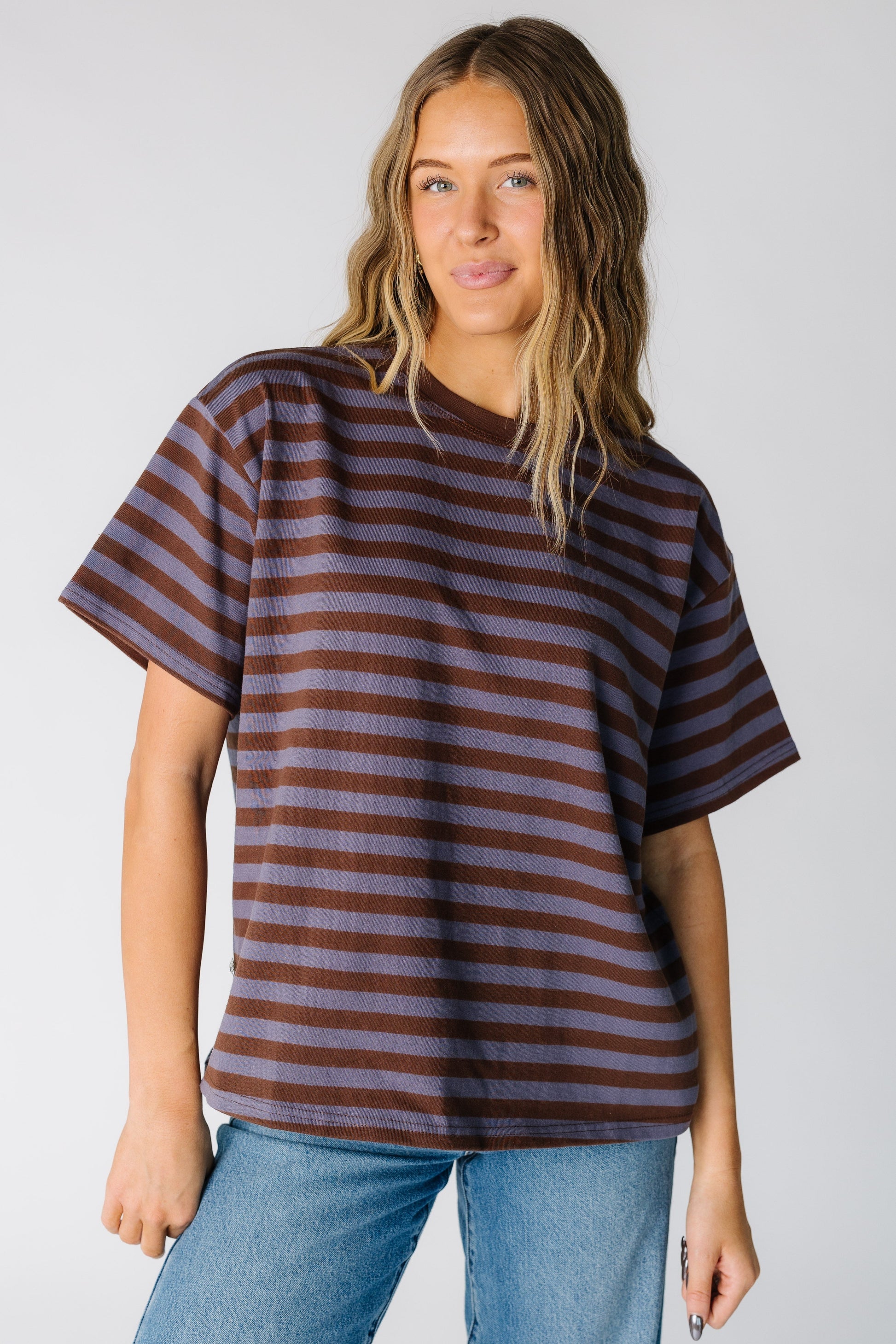 Woman wearing a loose fitting stripe tee in dusty blue and brown