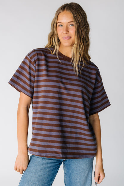 Woman wearing a loose fitting stripe tee in dusty blue and brown