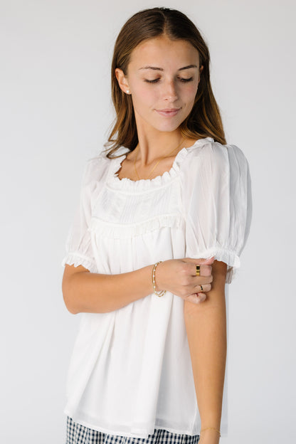 Side view of a woman wearing a white loose fitting top with short sleeves