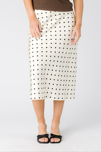Woman wearing a cream A-line midi skirt with black polka dots
