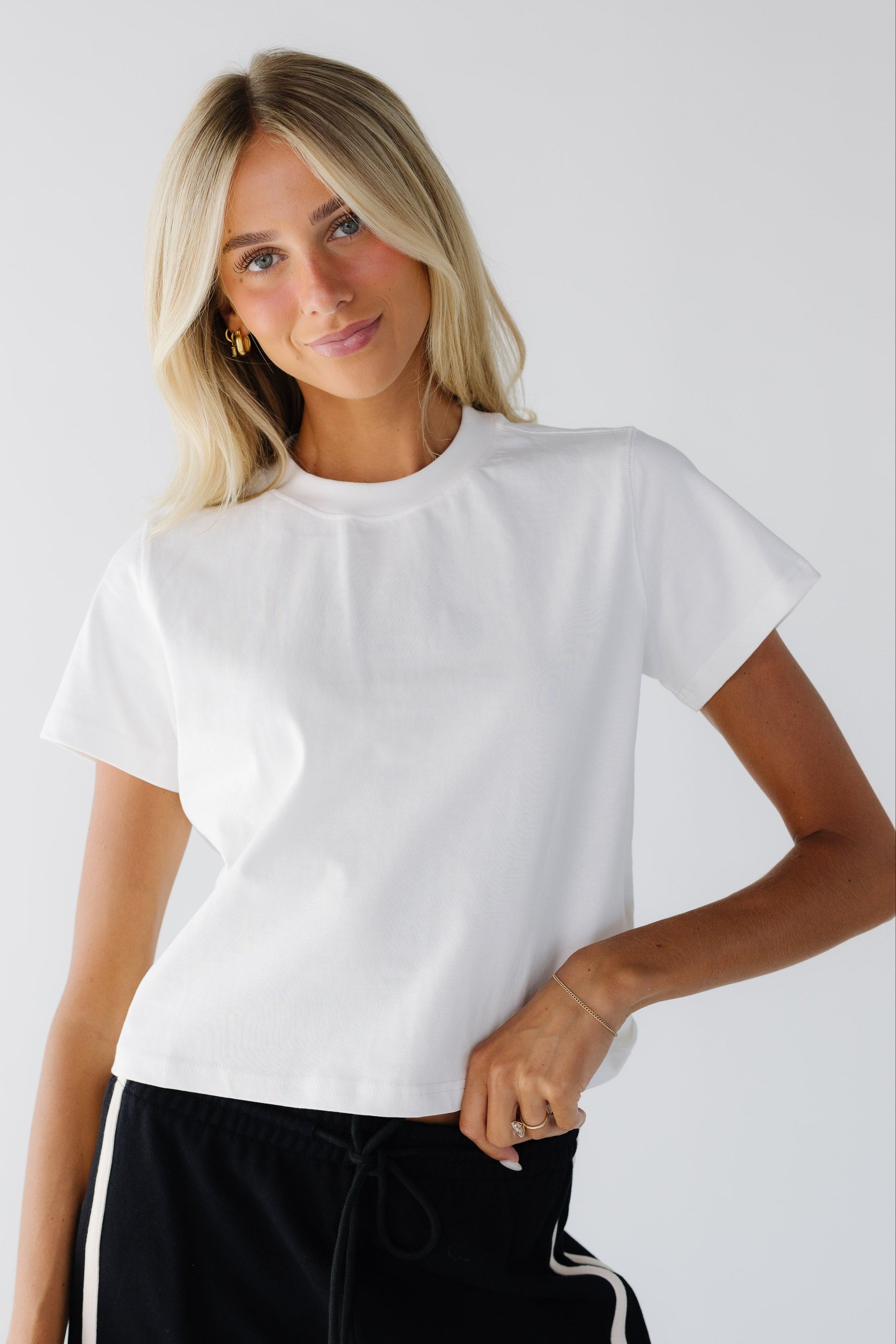 Woman wearing a loose fitting white short sleeve te with a wide crew neckline.