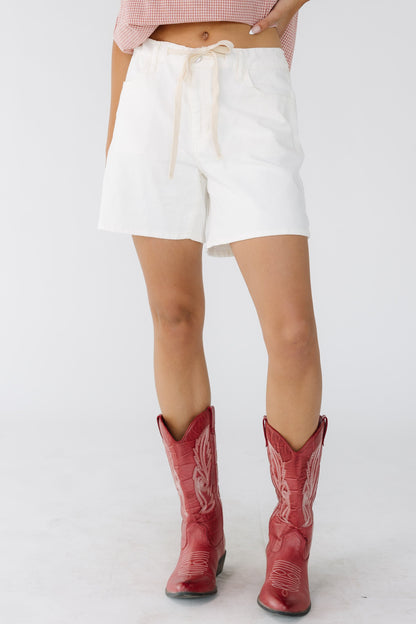 Woman wearing loose fitting off white short s with a drawstring waist.