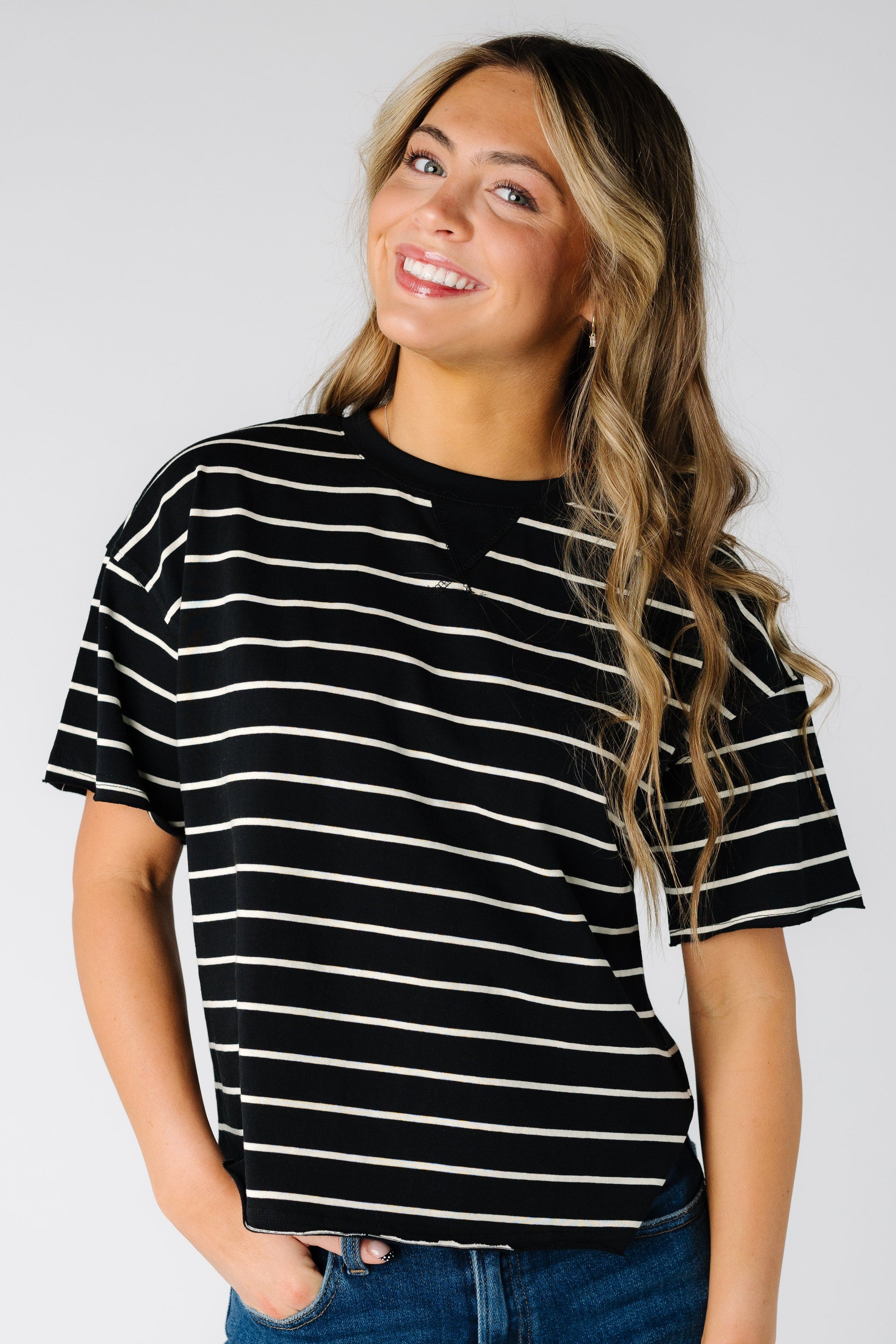 Woman wearing a black short sleeve tee with narrow white stripes.
