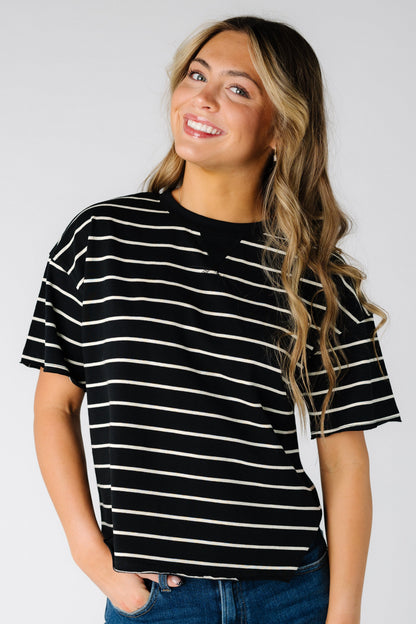 Woman wearing a black short sleeve tee with narrow white stripes.