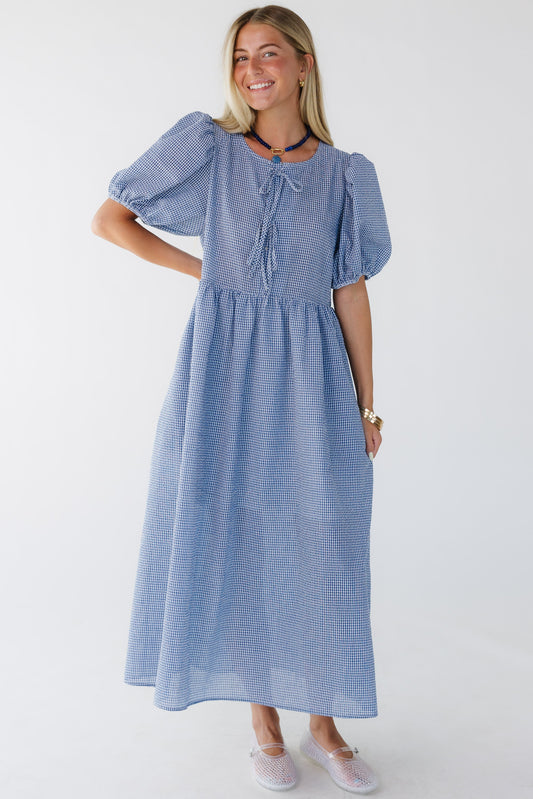 Young woman wearing a blue & white textured, loose fitting midi dress with a round neckline, and large balloon sleeves.