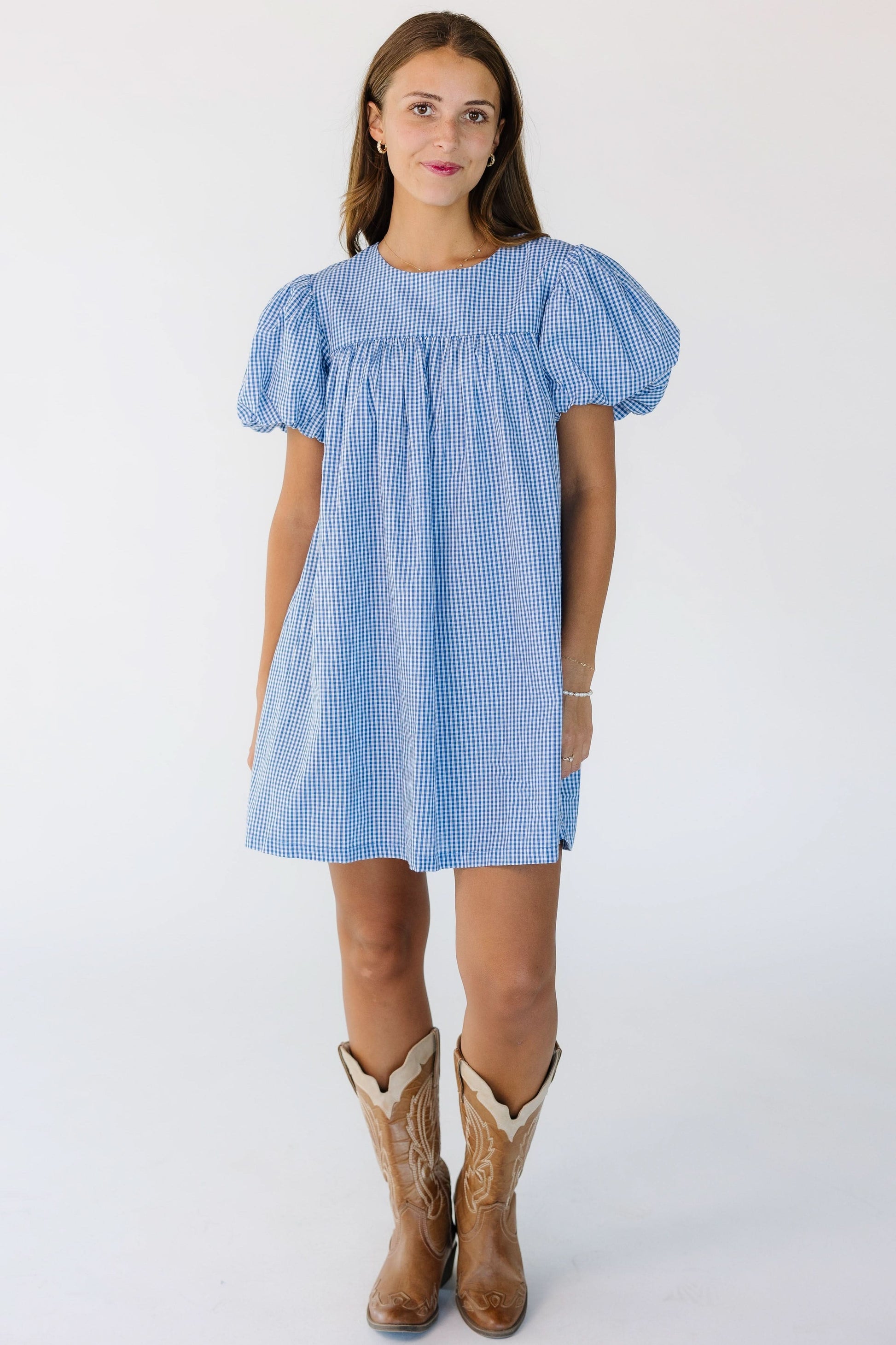 Young woman wearing a short blue and white baby doll dress with a short yoke and large puff sleeves.