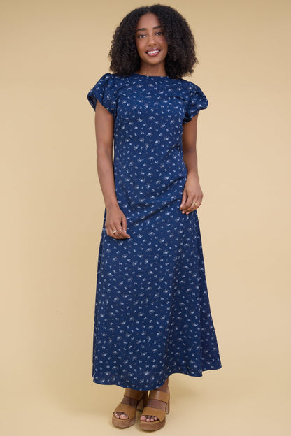 Young woman wearing a blue maxi with a round neckline and gathered cap sleeves.