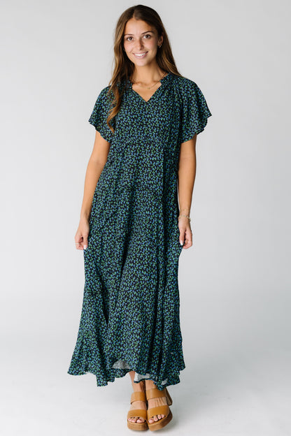 Woman wearing a blue and black floral print maxi dress with short flutter sleeves