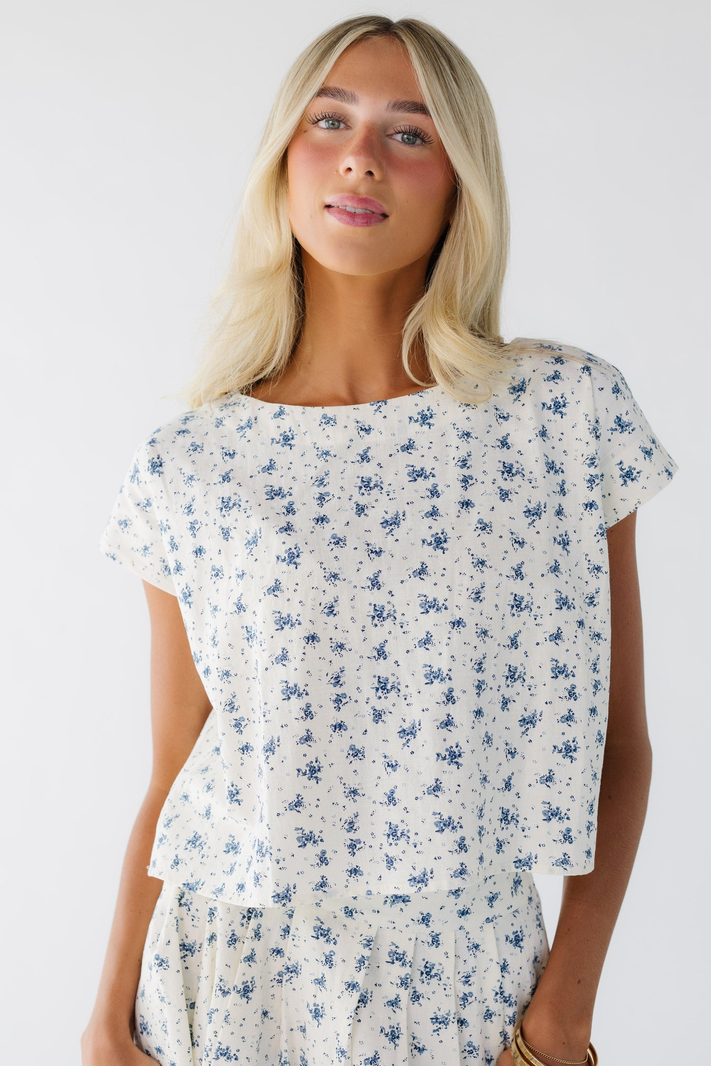 Woman wearing a cream & blue floral print  blouse.