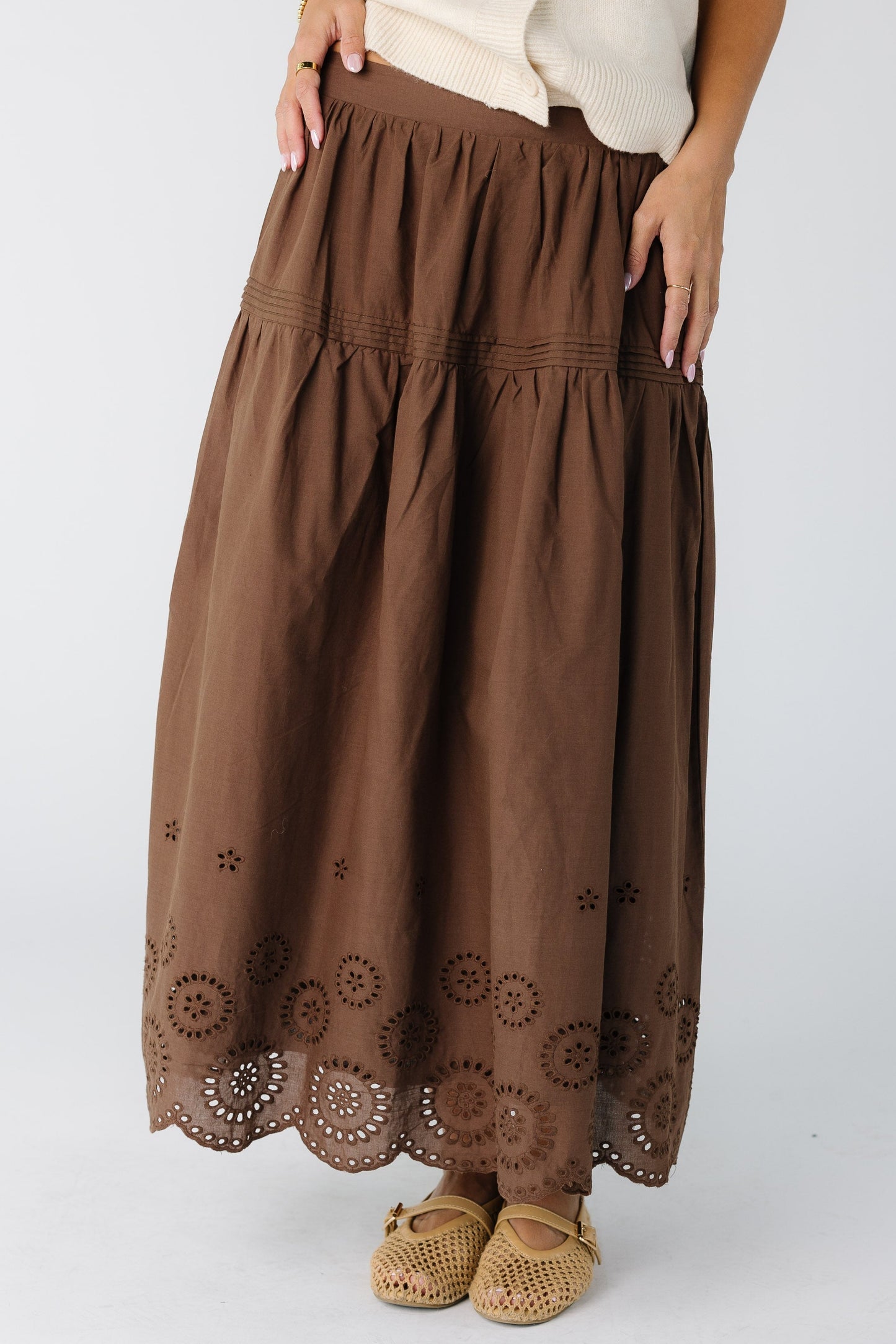 Woman wearing a modest brown skirt with a border eyelet pattern and drop waist
