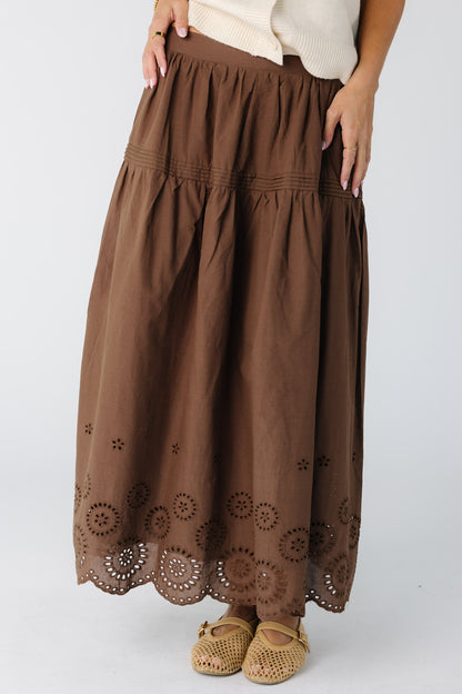 Woman wearing a modest brown skirt with a border eyelet pattern and drop waist