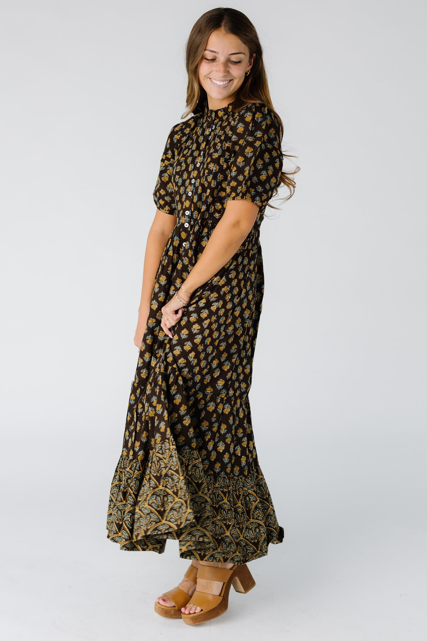 Woman wearing a brown midi-maxi dress with short sleeves and and round ruffled neckline