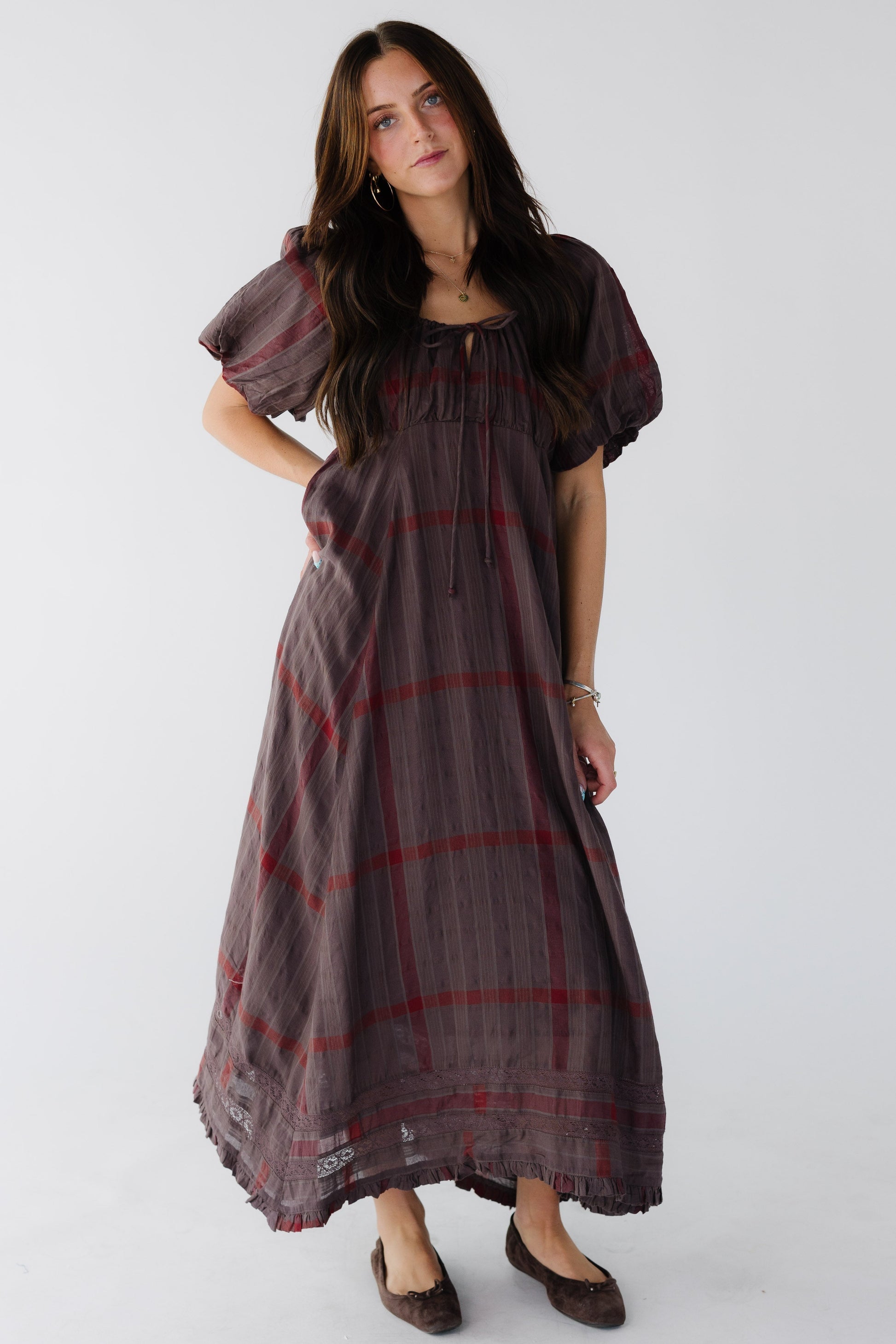 Woman wearing a brown and red plaid midi-maxi dress with large brown sleeves.