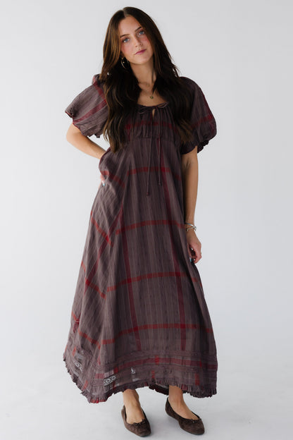 Woman wearing a brown and red plaid midi-maxi dress with large brown sleeves.