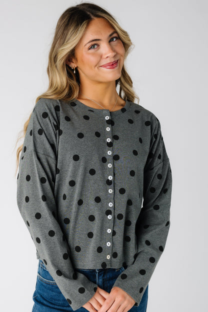 Woman wearing a long sleeve charcoal grey cardigan with black polka dots