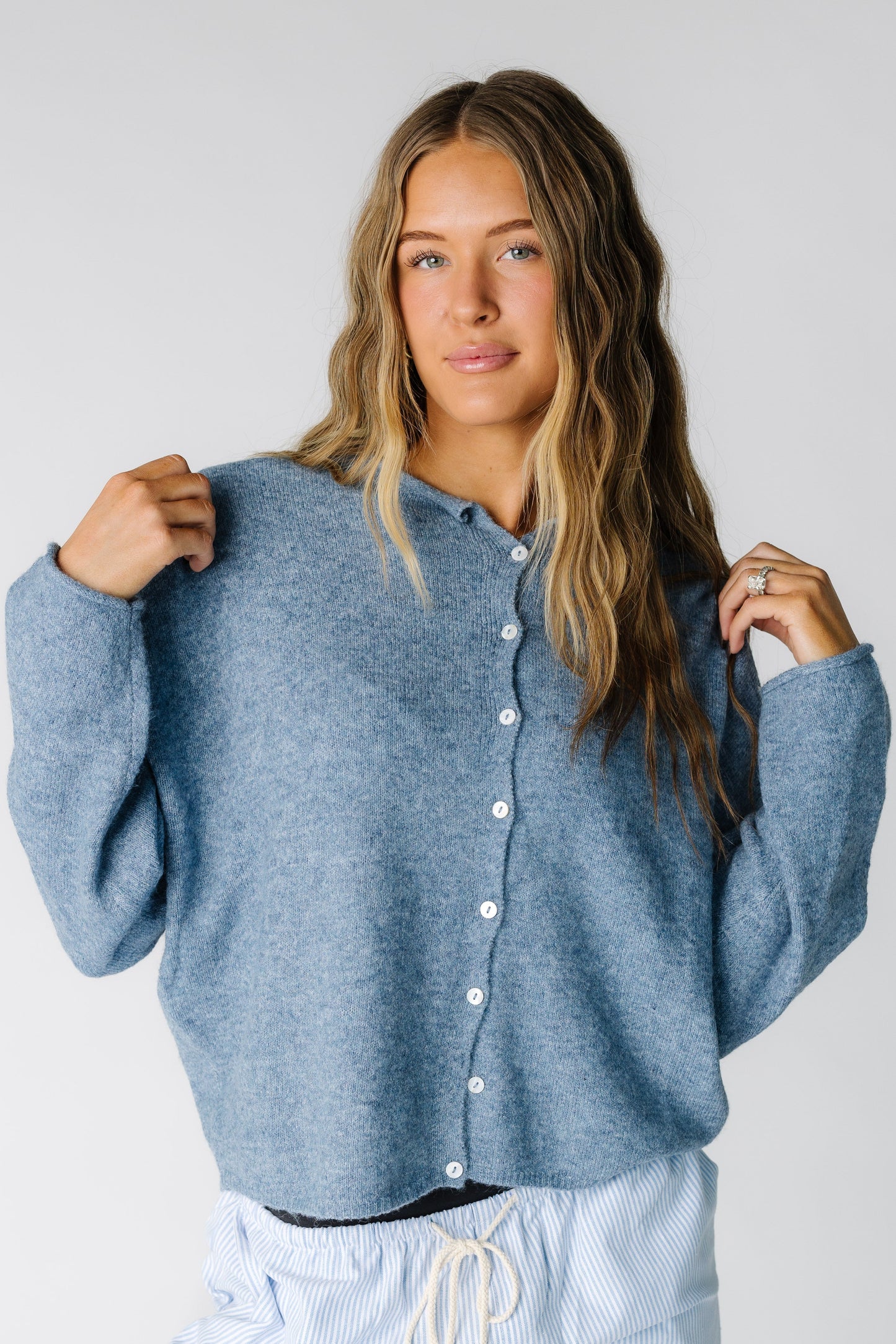 Woman wearing a modest dusty blue button cardigan with a round neckline with rolled collar and long sleeves