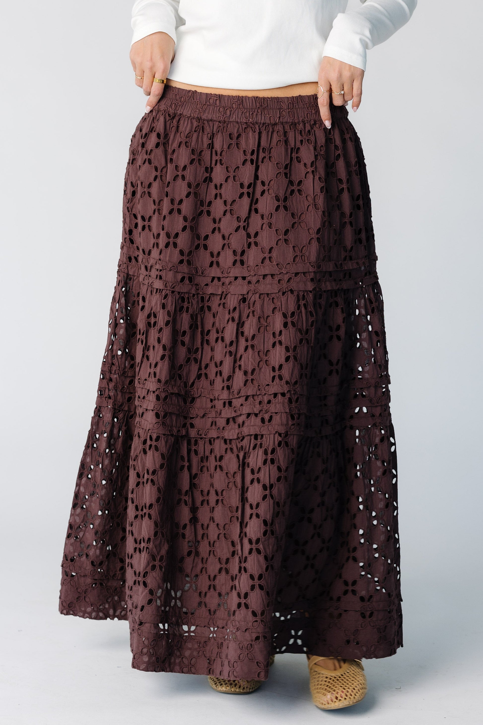 Woman wearing a brown eyelet maxi skirt with folded pleats and tiers