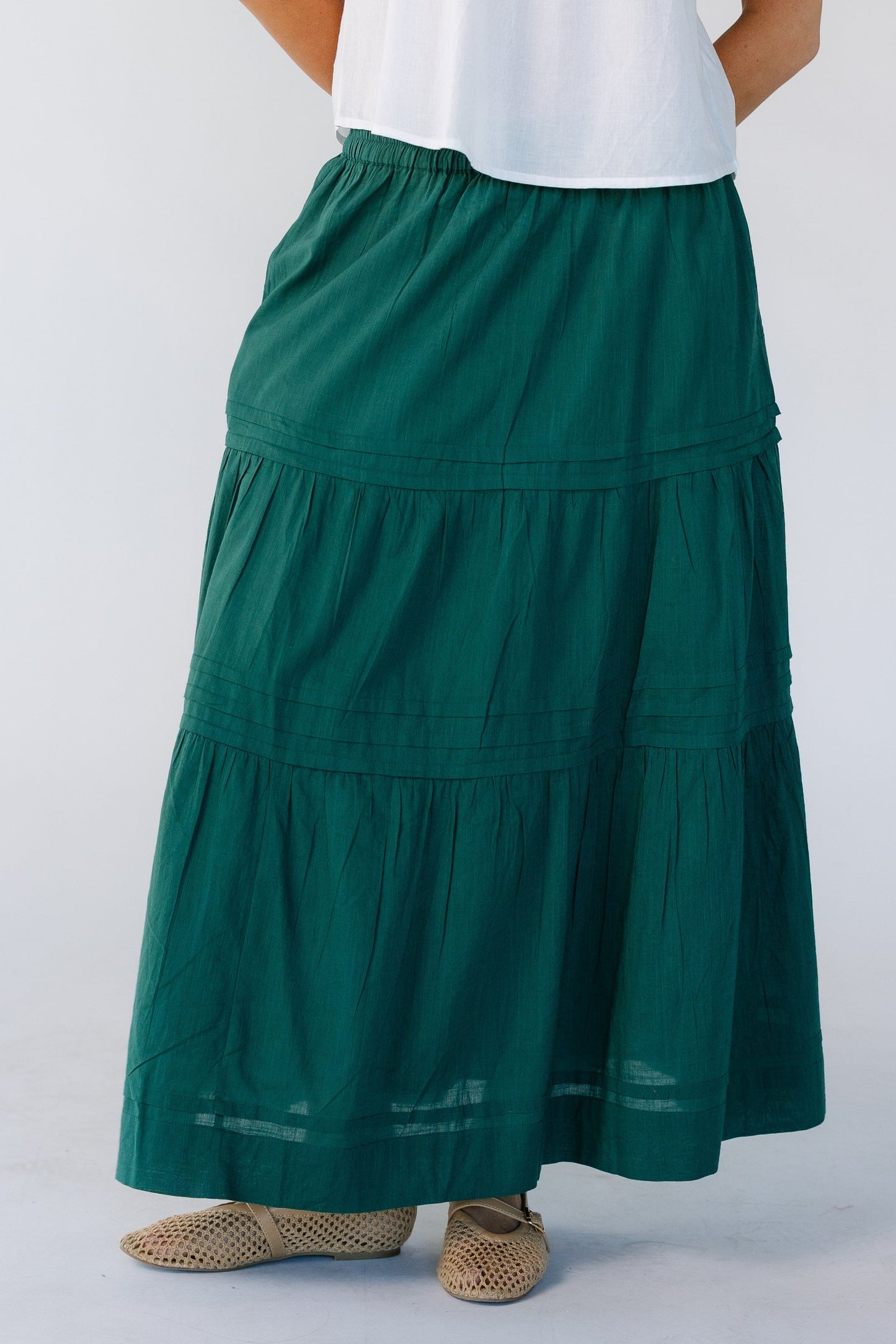 Woman wearing a  green tiered midi skirt with an elastic waistband.