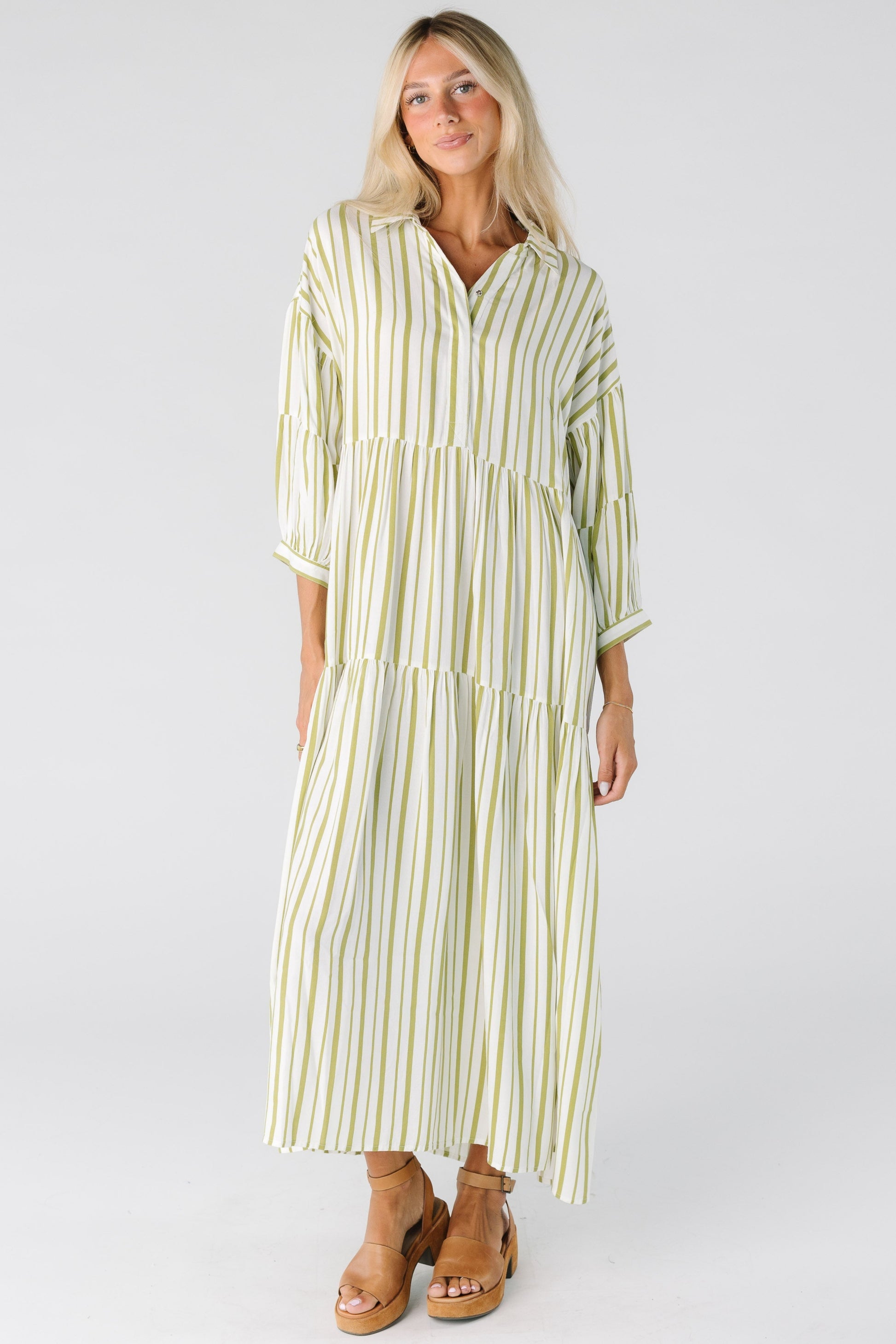 Woman in an ivory and green stripe loose fitting dress with long sleeves