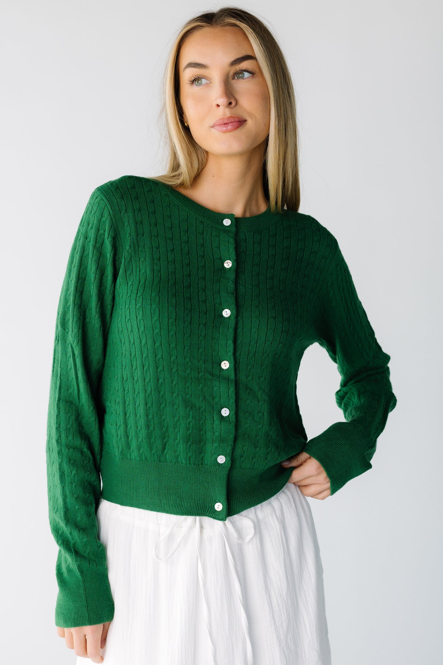 Woman wearing a green long sleeve cardigan with a round neckline and white buttons