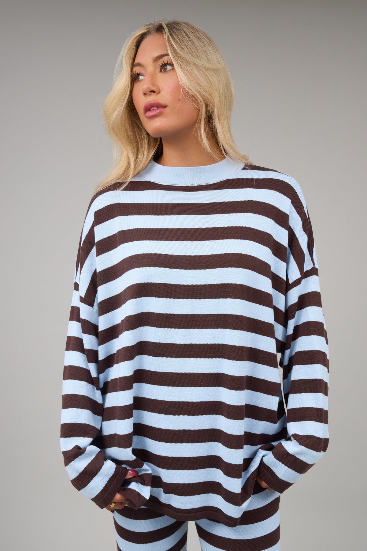 Young woman wearing a modest loose fitting light blue & brown wide stripe with long sleeves.