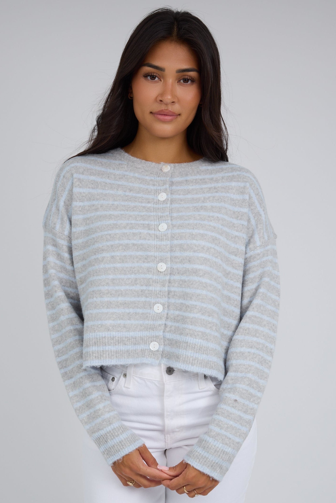 Woman wearing a  boxy loose fitting button down cardigan with long sleeves and a round crew neckline.