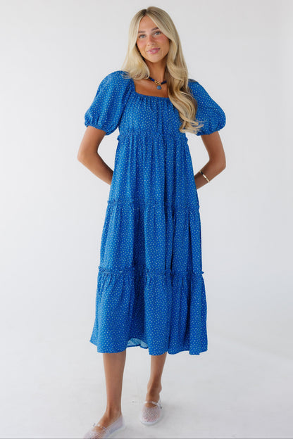 Young woman wearing a modest  blue floral tiered dress with a square neckline with balloon sleeves.