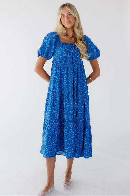 Young woman wearing a modest  blue floral tiered dress with a square neckline with balloon sleeves.