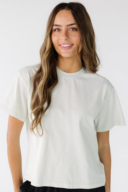 Young woman wearing an off white short sleeve tee with a crew neckline.