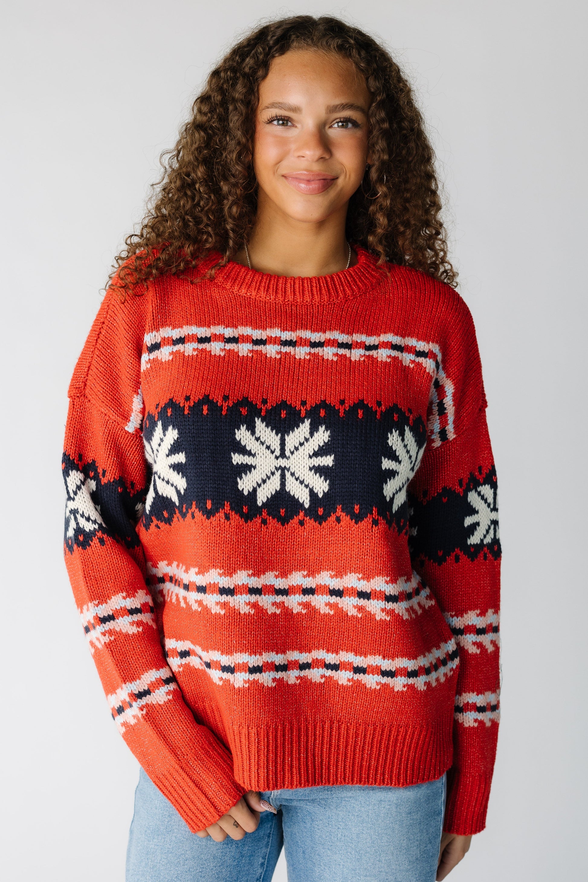 Woman wearing a modest red pullover sweater with snowflake graphic stripe with crew neckline and long sleeves