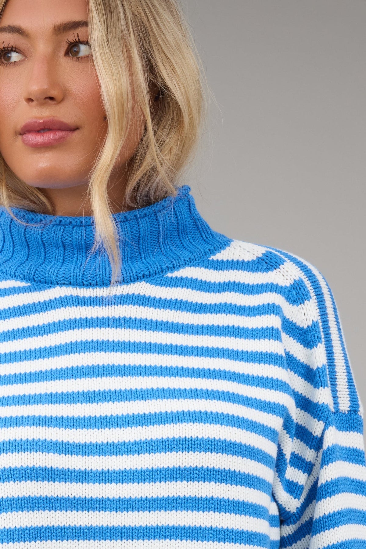 Close view of a woman wearing a blue & white stripe sweater with a blue turtleneck.
