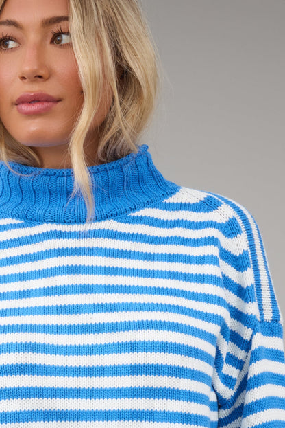 Close view of a woman wearing a blue & white stripe sweater with a blue turtleneck.