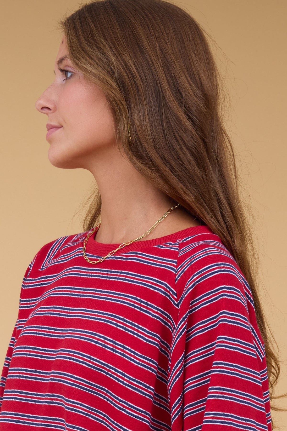 Close view of a woman wearing a red & navy stripe long sleeve sweatshirt with a crew neckline.