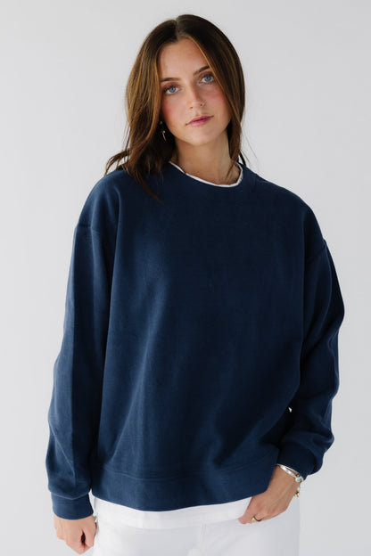 Young woman wearing a navy oversized sweathirt with a white tee crew collar.