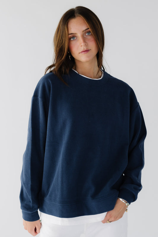 Young woman wearing a navy oversized sweathirt with a white tee crew collar.