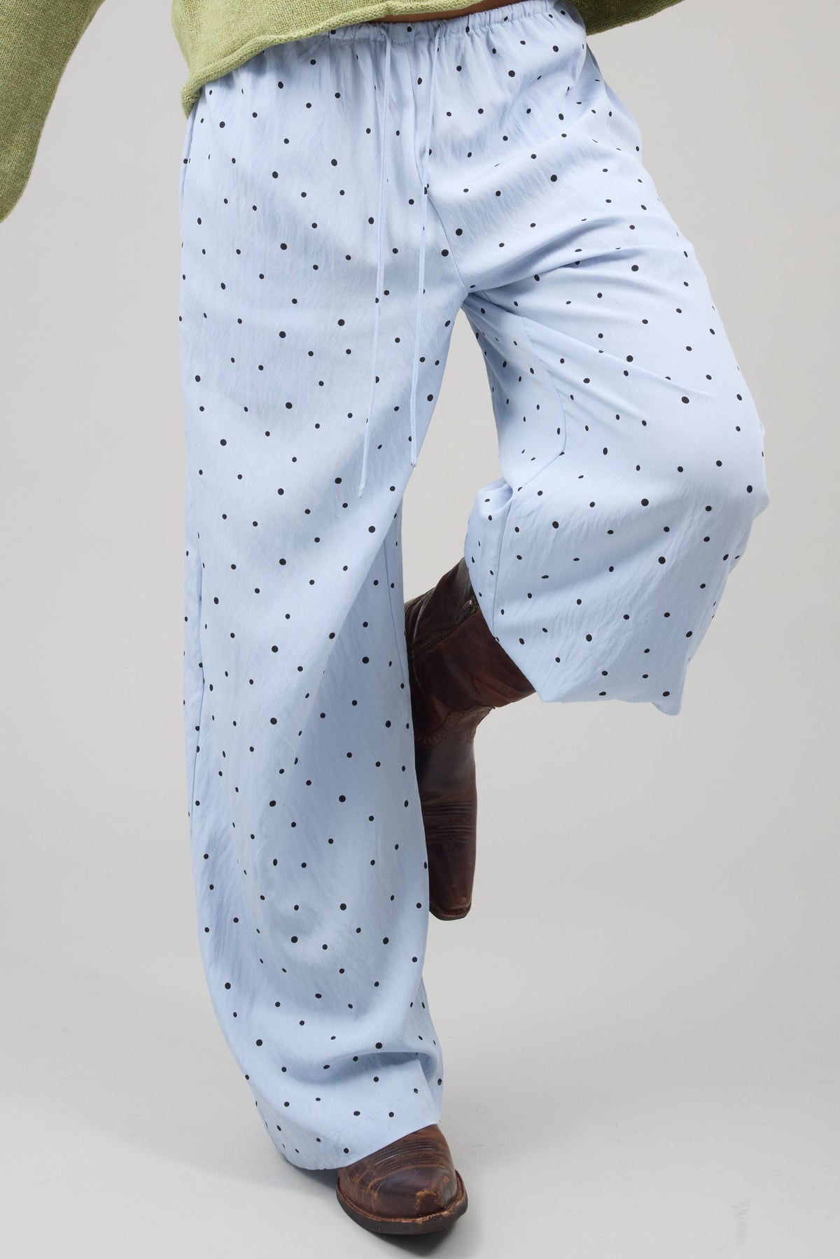 Young woman wearing wide leg polka dot pants with a drawstring waist.