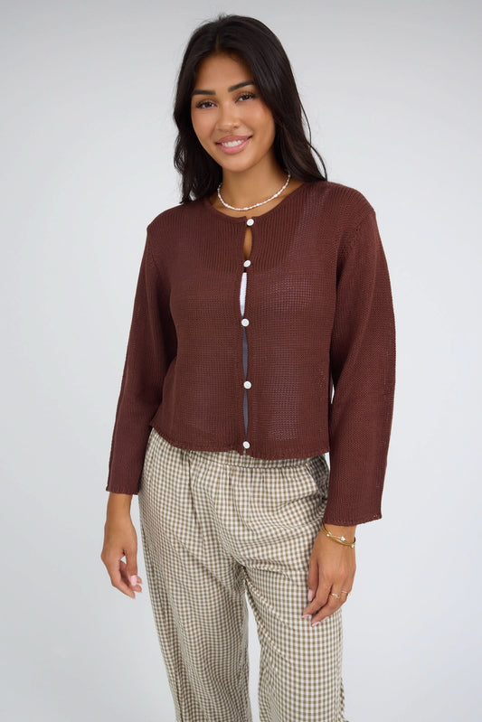 Young woman wearing a modest, loosely knit button down cardigan with long sleeves.