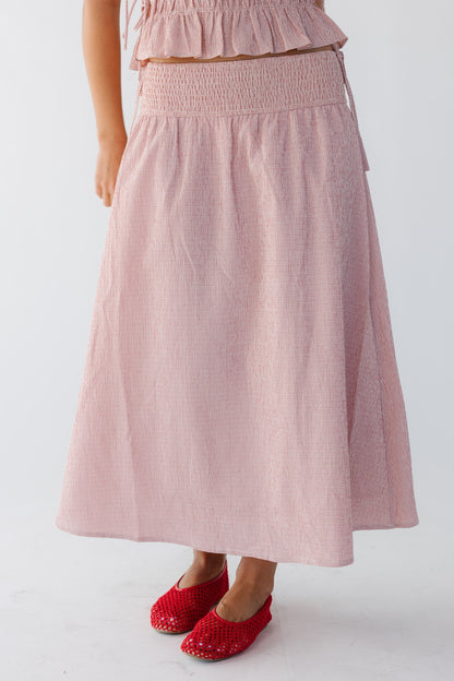 Woman wearing a pink and white gingham midi-maxi skirt with a wide elastic drop waist. 