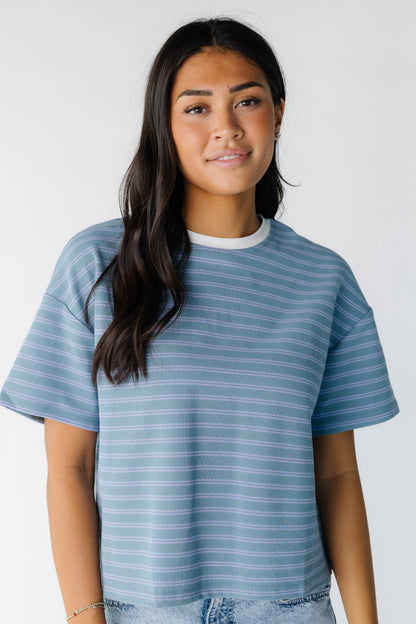 Young woman wearing a modest green tee with blue stripe with a crew neckline in white with short sleeves.