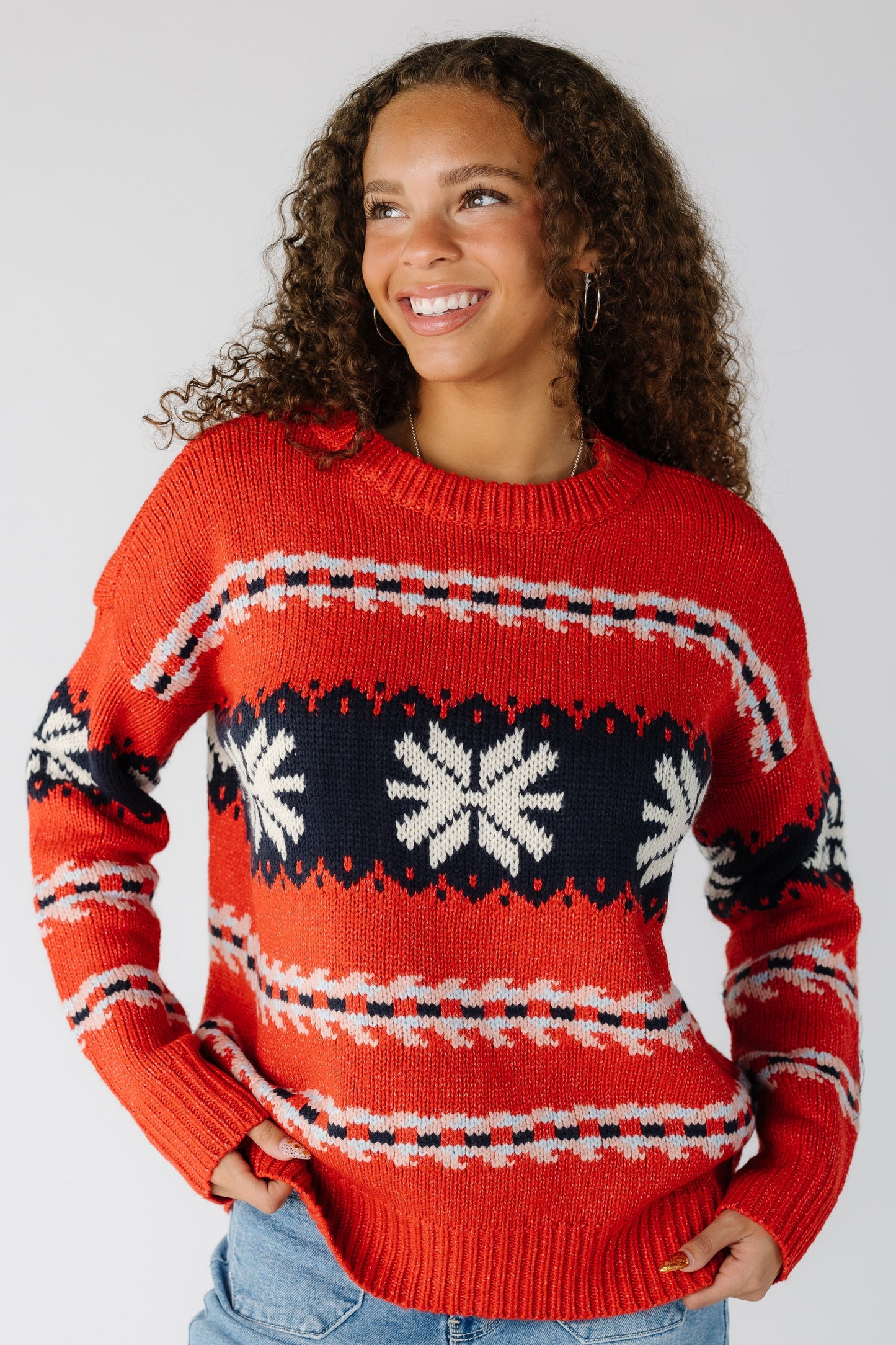 Woman wearing a red long sleeve sweater with a snowflake graphic