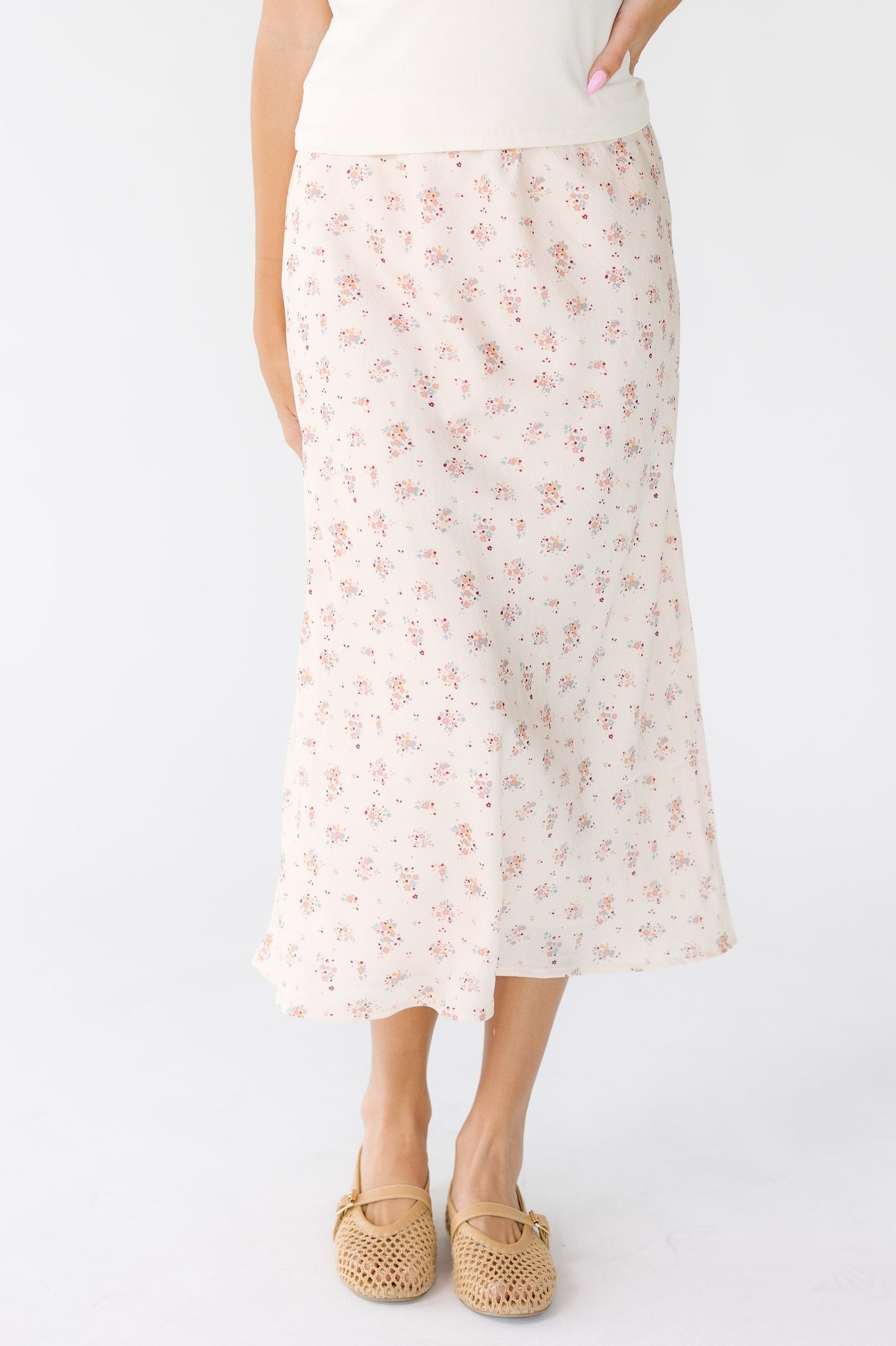 Young woman wearing an ivory and pink A-line midi skirt.