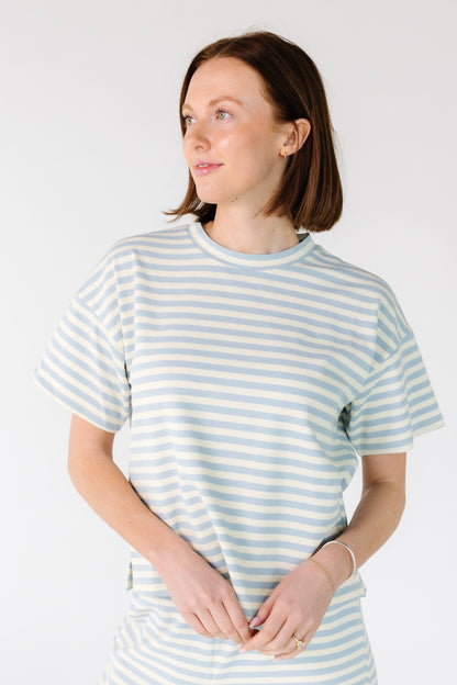 Woman wearing a modest white and light blue stripe tee with a crew neckline and short sleeves.